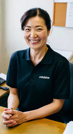 Smiling woman in an Infoblox polo shirt at her desk.